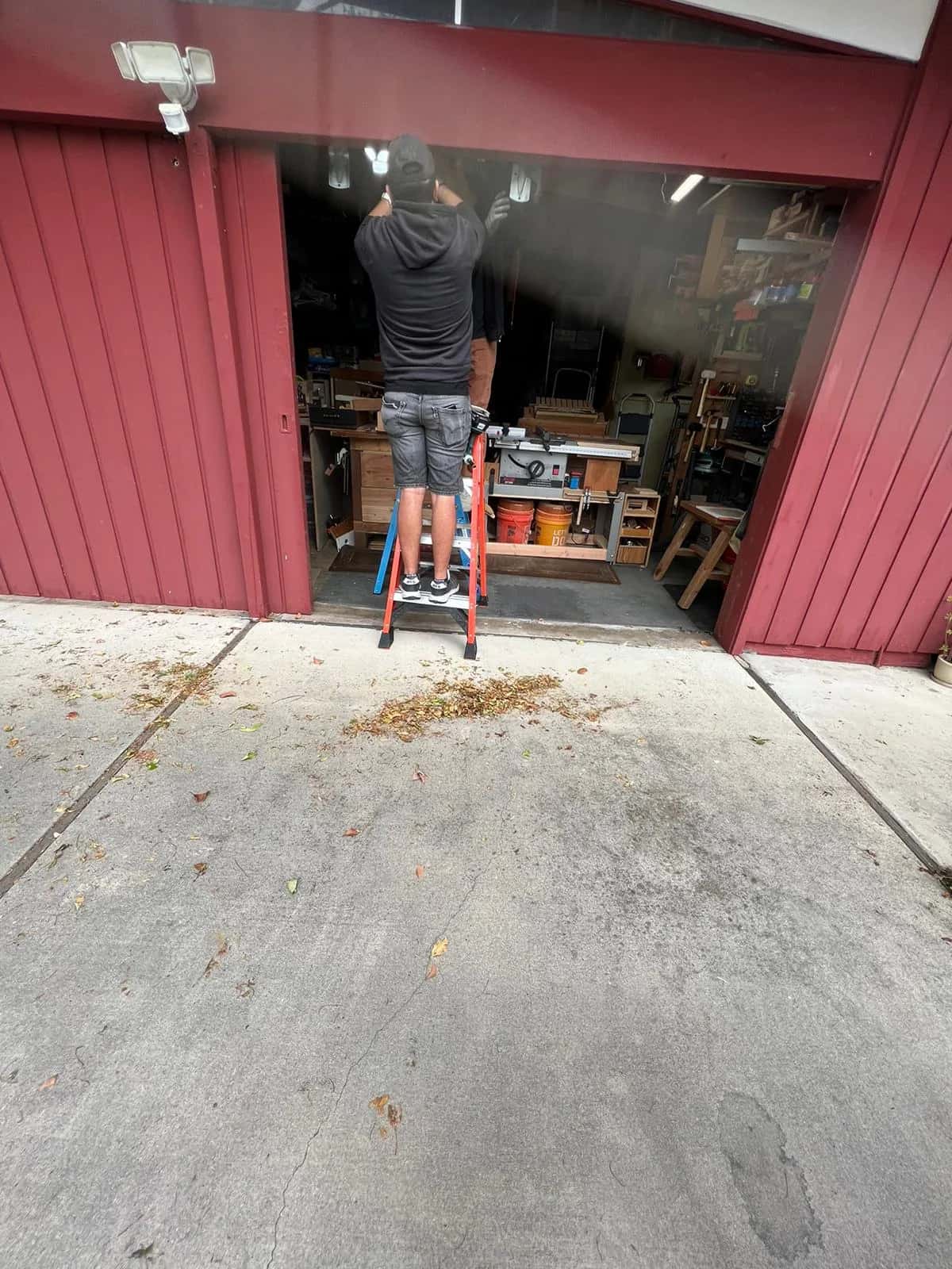 WeDo technician on a ladder repairing a garage door